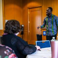 Man presenting to a group of people, gesturing while speaking